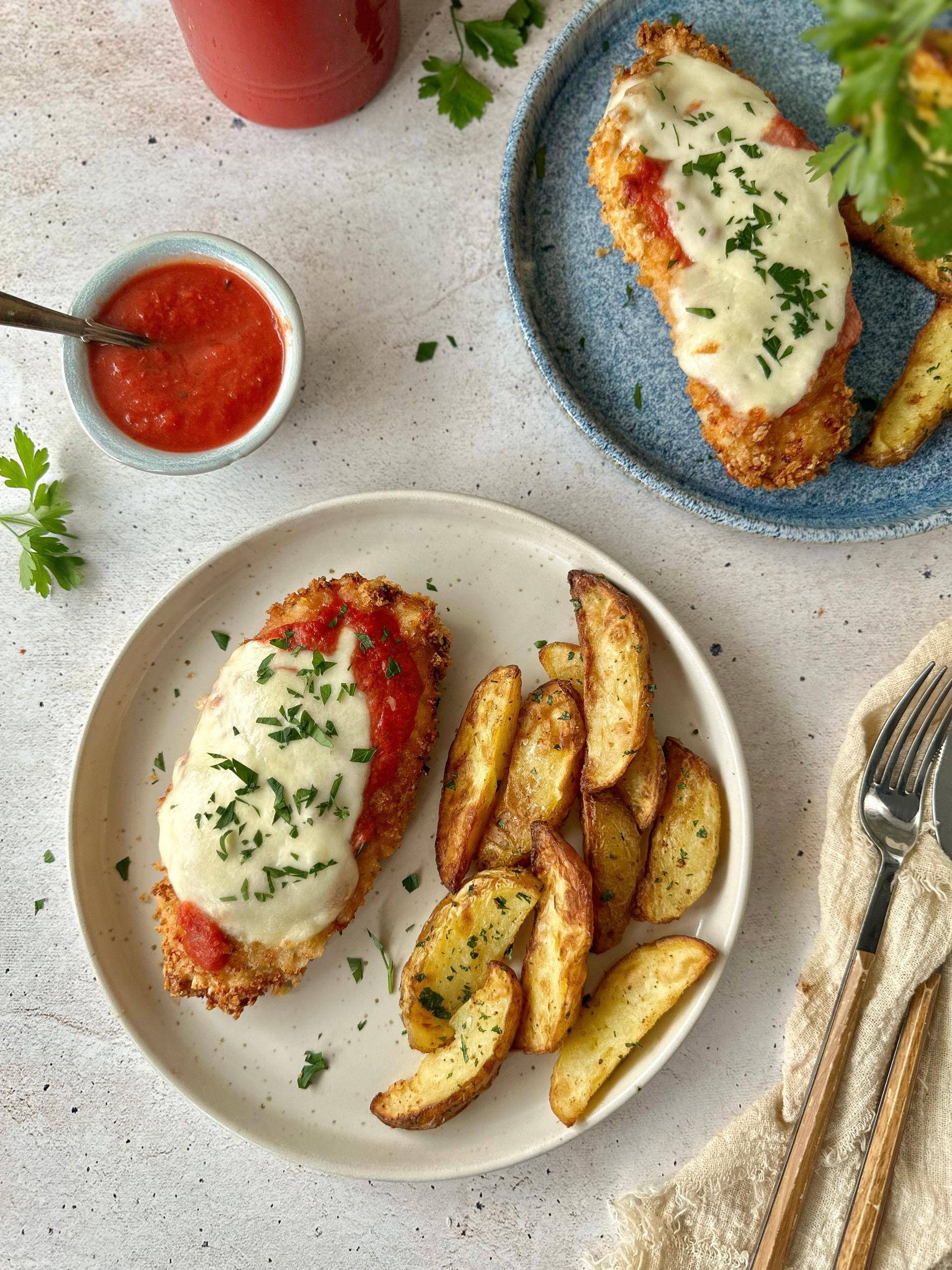 Kurczak parmigiana w chrupiącej panierce z sosem pomidorowym i mozzarellą z dodatkiem czosnkowych ziemniaczków - przepisy EASY FRY & GRILL 2 in 1 MECHANICAL | Tefal