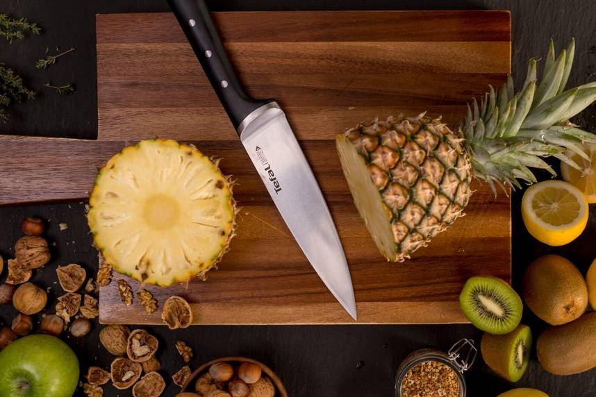 Nóż Tefal na drewnianej desce z ananasem i kiwi